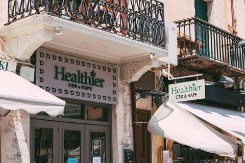 Exterior storefront of Healthier CBD & Vape shop with signage and white awnings.